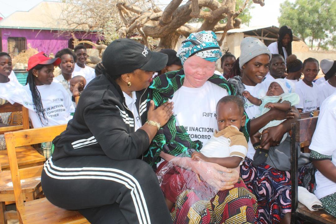 Vivian Sirikwa embracing programme participants holding their children